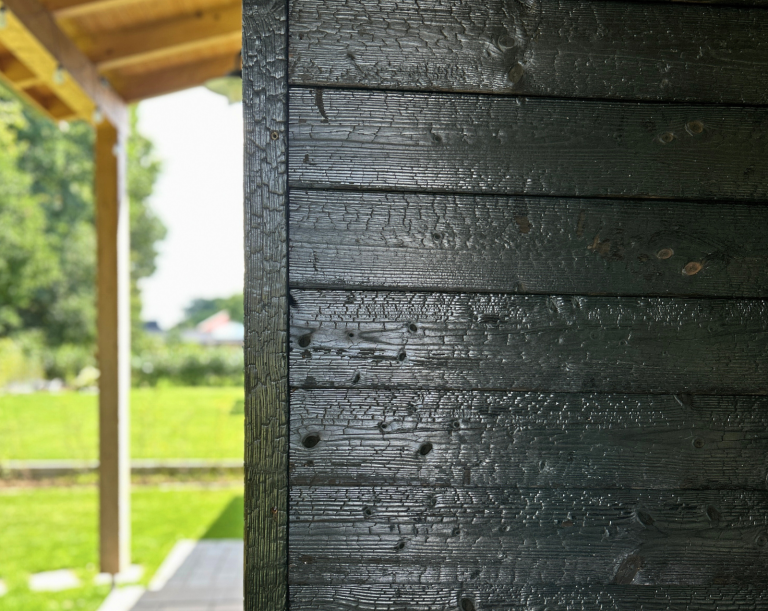 Nahaufnahme der geflammten, karbonisierten Holzfassade (Carboris) mit sichtbarer Struktur und Maserung