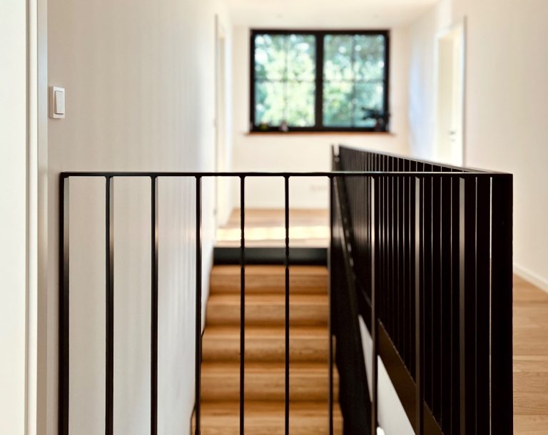 Blick auf Galerie mit schwarzem Metallgeländer und Holzstufen im Obergeschoss