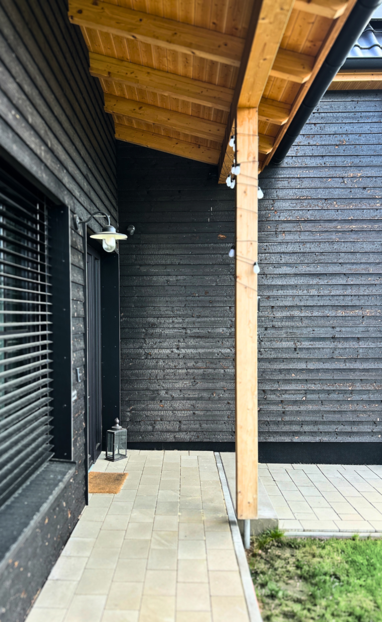 Detail des Hauseingangs mit Vordach und geflammter, karbonisierter Holzfassade (Carboris) an der Außenwand