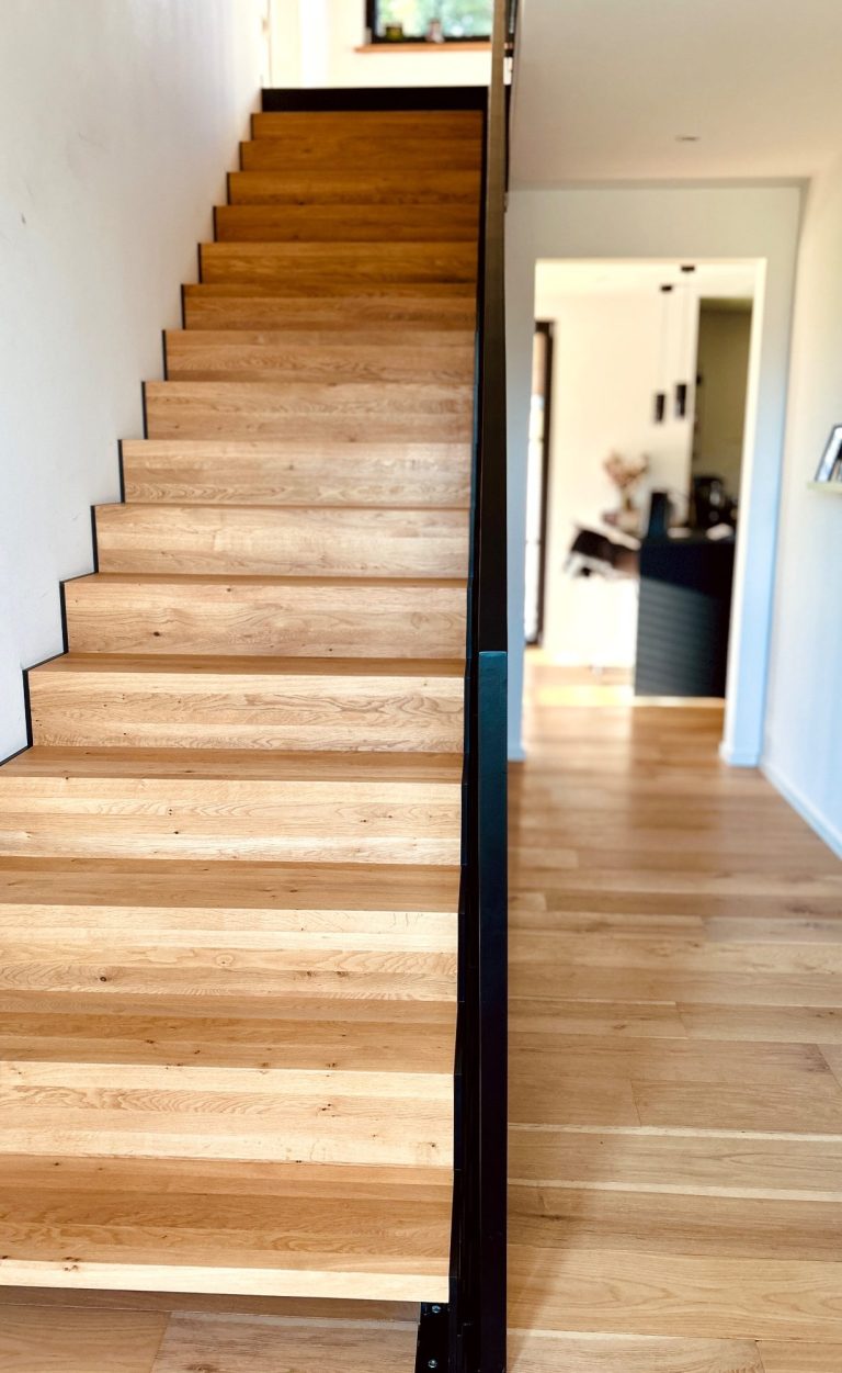 Moderne Innentreppe aus Holz mit schwarzem Geländer im Wohnhaus