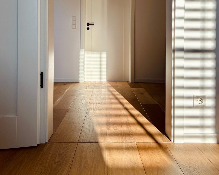 Heller Flur mit Holzboden, weißer Innentür und Lichteinfall durch Fenster